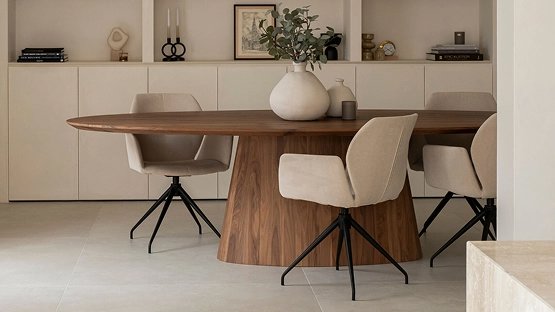 Notenhouten ovale eettafel van Table du Sud met lichte eetkamerstoelen